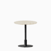 Round dining table with terrazzo top and metal pedestal base.