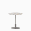 Round dining table with terrazzo top and metal pedestal base.