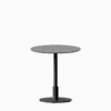 Round dining table with terrazzo top and metal pedestal base.