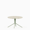 Round terrazzo table with speckled stone top and green aluminium base.
