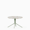 Round terrazzo table with speckled stone top and green aluminium base.