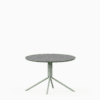 Round terrazzo table with speckled stone top and green aluminium base.